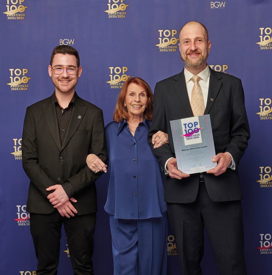 Joshua Jäger und Lars Rudloff stehen mit Senta Berger vor einer TOP 100 Akustiker-Fotowand; Lars Rudloff hält die Auszeichnung in den Händen.