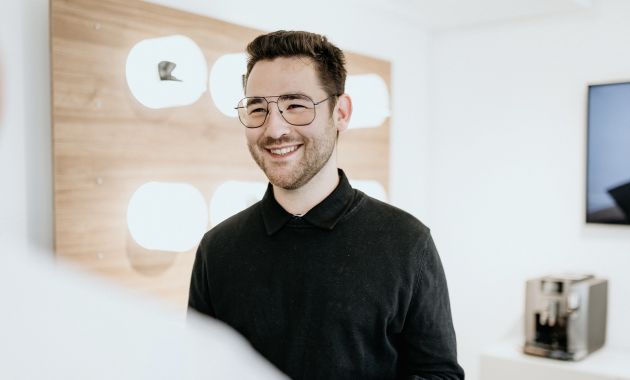 Joshua Jäger steht lächelnd in einem hellen Fachgeschäft.