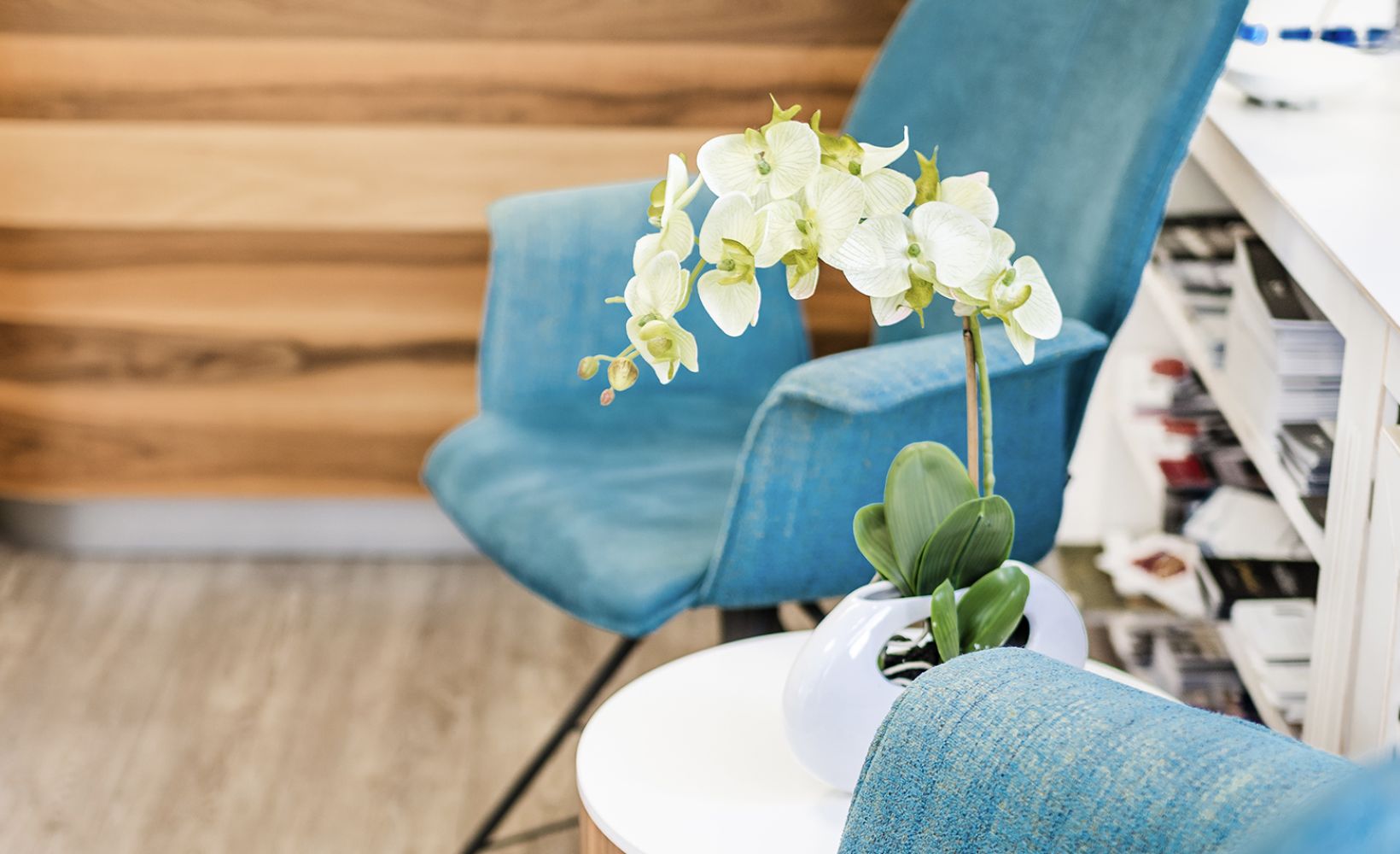 Wartebereich mit blauen Sesseln, weißem Beistelltisch und einer Orchidee im Männing Fachgeschäft Wülfrath.