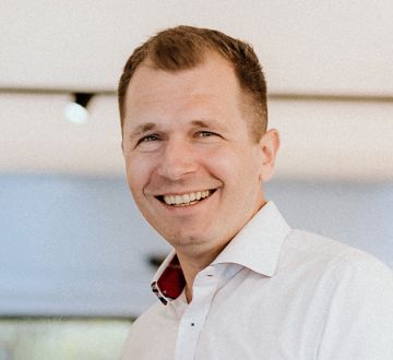 Michael Männing steht lächelnd in einem hellen Fachgeschäft und trägt ein weißes Hemd.