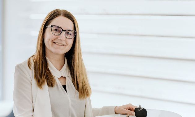 Jessica Heiligenhaus steht lächelnd in einem hellen Raum an einem Tresen.
