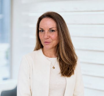 Kathrin Schümmer sitzt in einem hellen Raum und blickt freundlich in die Kamera.